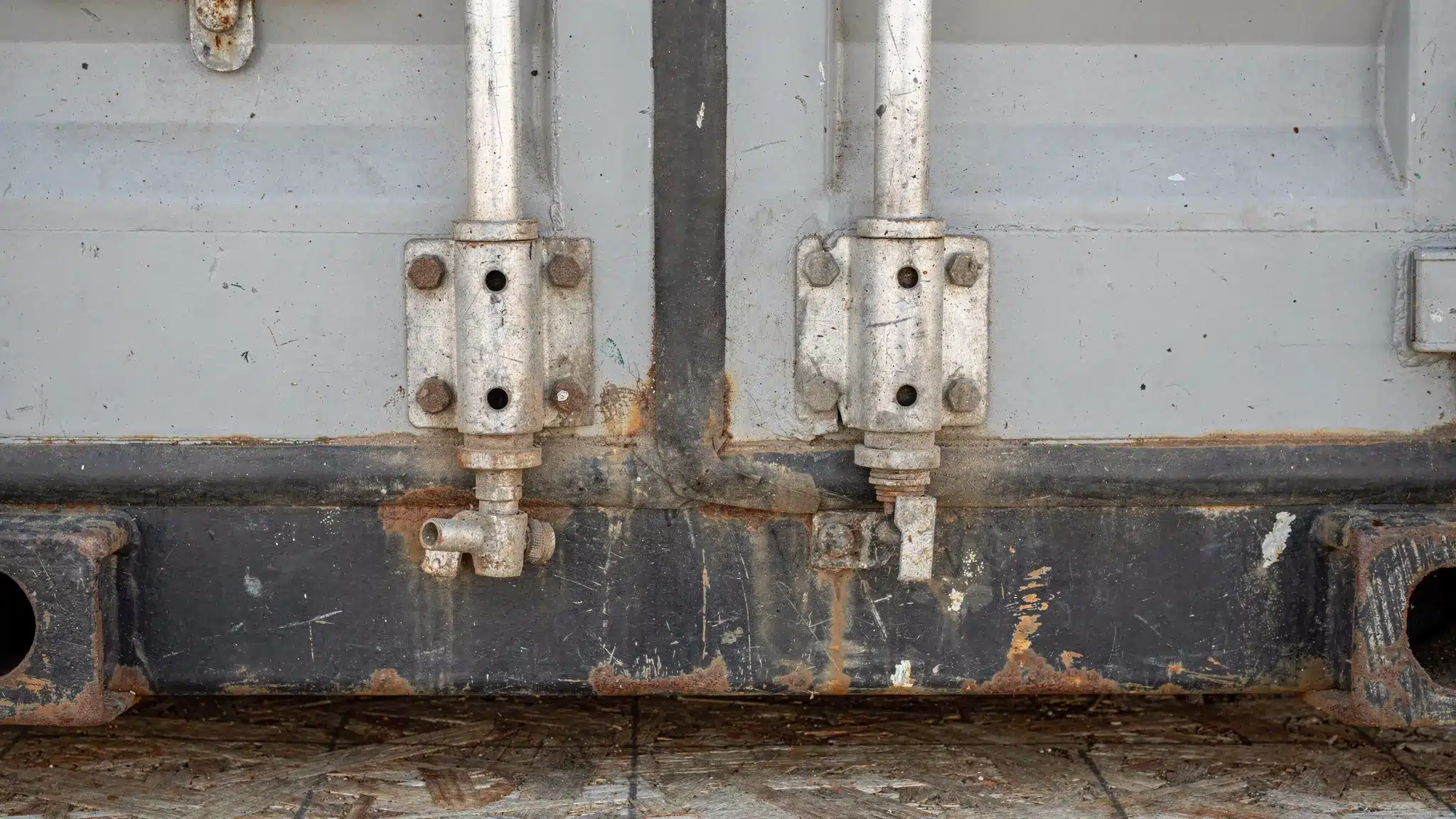Storage Containers for Rental: Delivery, Access, and Damage Fees Close-up visual of common shipping container wear points: door locking rods and hinges, rubber door gasket, corner casting, and plywood floor near the threshold with minor scuffs.