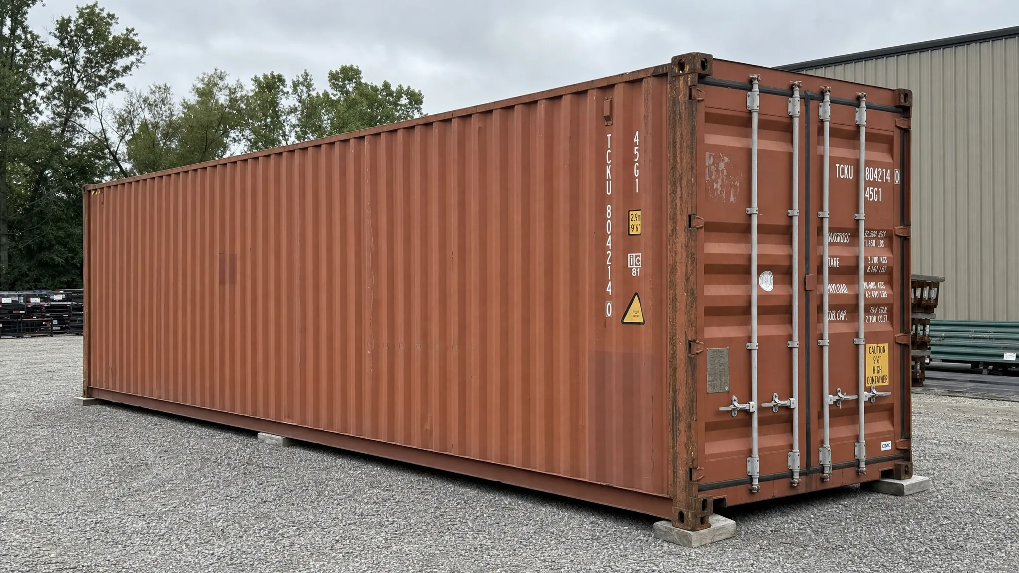 Used Containers for Sale Near Me: How to Spot Value A used 40ft shipping container in good structural condition sitting on a level gravel pad at a commercial property, shown from a side angle with visible Corten Steel side panels, secure cargo doors, and clear space for delivery truck access.