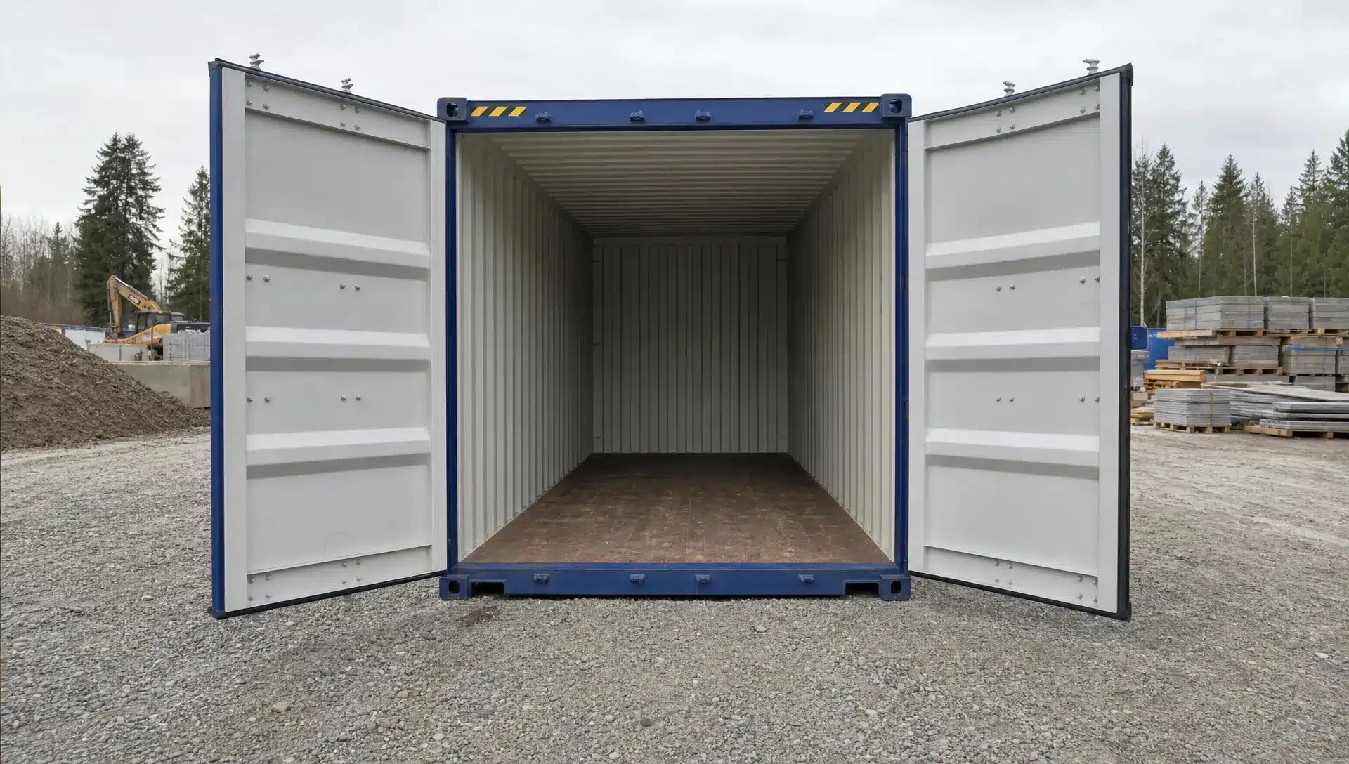 How to Compare Conex Containers for Sale in Your Area A clean Conex shipping container on a level gravel pad at a construction site, shown from a low front angle with open doors facing the camera, a dry interior, Corten Steel walls, a wood floor, and clear space for a delivery truck to maneuver.